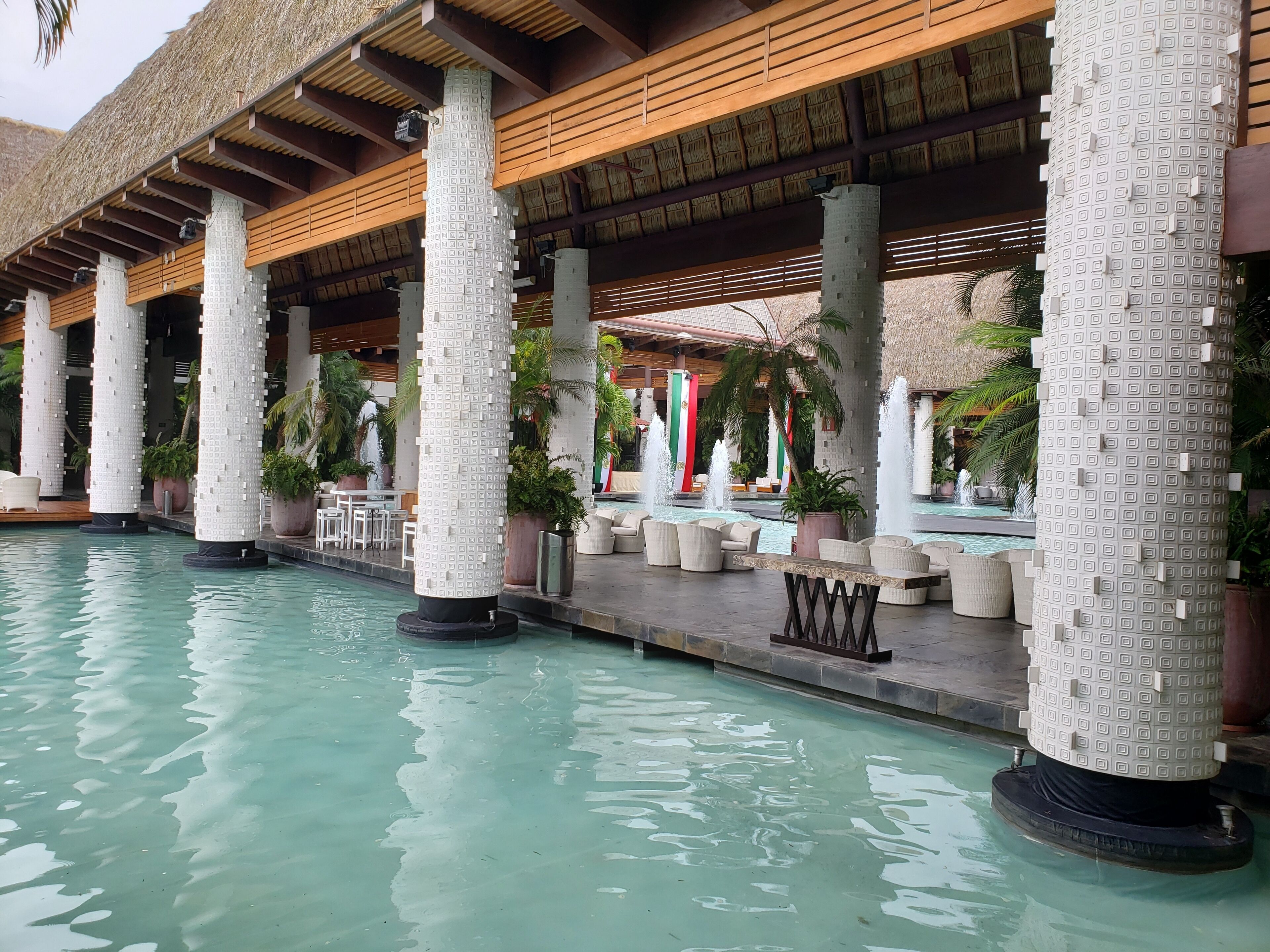 A pool area with water features, seating, and columns.