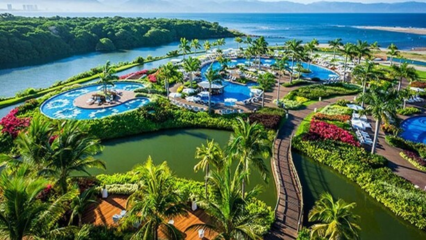 Un complexe hôtelier doté de plusieurs piscines, d’une végétation luxuriante et offrant une vue sur l’océan.