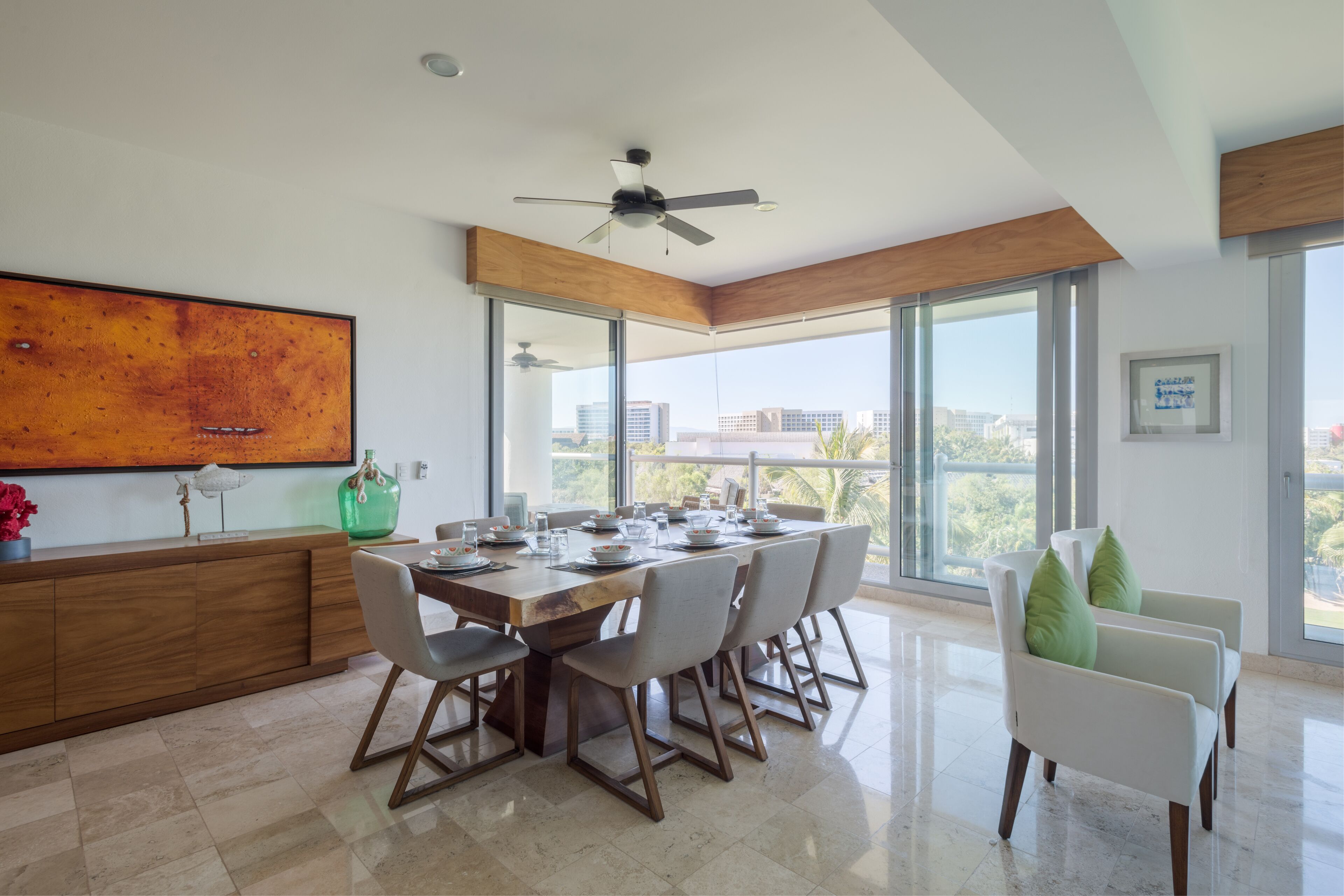 A modern dining area with a large table, chairs, and a ceiling fan.