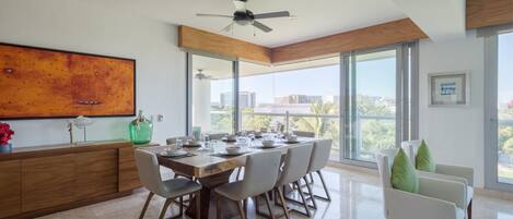 A modern dining area with a large table, chairs, and a ceiling fan.