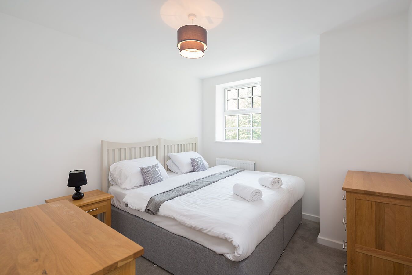 A bedroom with a bed, bedside tables, a lamp, a window, and a radiator.