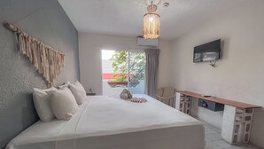 A hotel room with a bed, a desk, a TV, and a view of the outdoors. - Ahava Hotel (Playa del Carmen)