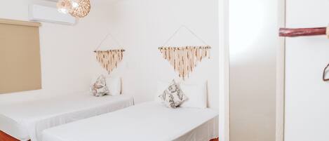 A hotel room with two beds, a wooden door, and a hanging light fixture.