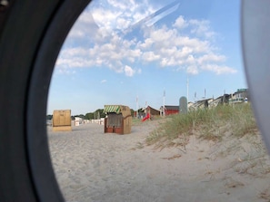 Ein Strand mit Sand, einigen Strandkörben und blauem Himmel.