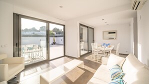 Ein modernes Wohnzimmer mit einer Couch, einem Couchtisch und einem Essbereich mit Stühlen und einem Tisch.