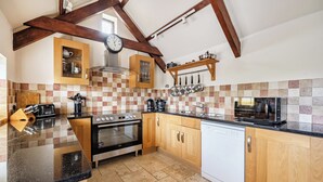 Une cuisine avec des meubles de rangement en bois, une cuisinière, un four, un lave-vaisselle et un four à micro-ondes.