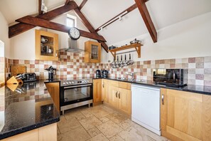 A kitchen with wooden cabinets, a stove, an oven, a dishwasher, and a microwave. - Granary Barn, A Rural Retreat - Private Hot Tub, (Winkleigh)