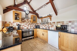 Una cocina con armarios de madera, estufa, horno, lavavajillas y microondas.