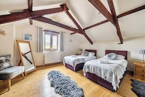 A bedroom with two beds, a wooden floor, a window, and a radiator. - Granary Barn, A Rural Retreat - Private Hot Tub, (Winkleigh)