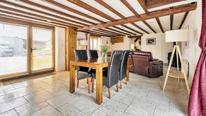 Un coin repas avec une table et des chaises en bois, un canapé en cuir et un rideau rouge.