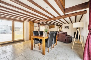 Un comedor con una mesa y sillas de madera, un sofá de cuero y una cortina roja.