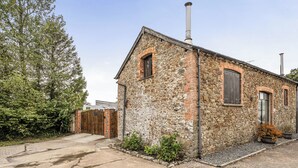 Un bâtiment en pierre doté d’une cheminée, d’un portail en bois et d’une allée pavée.