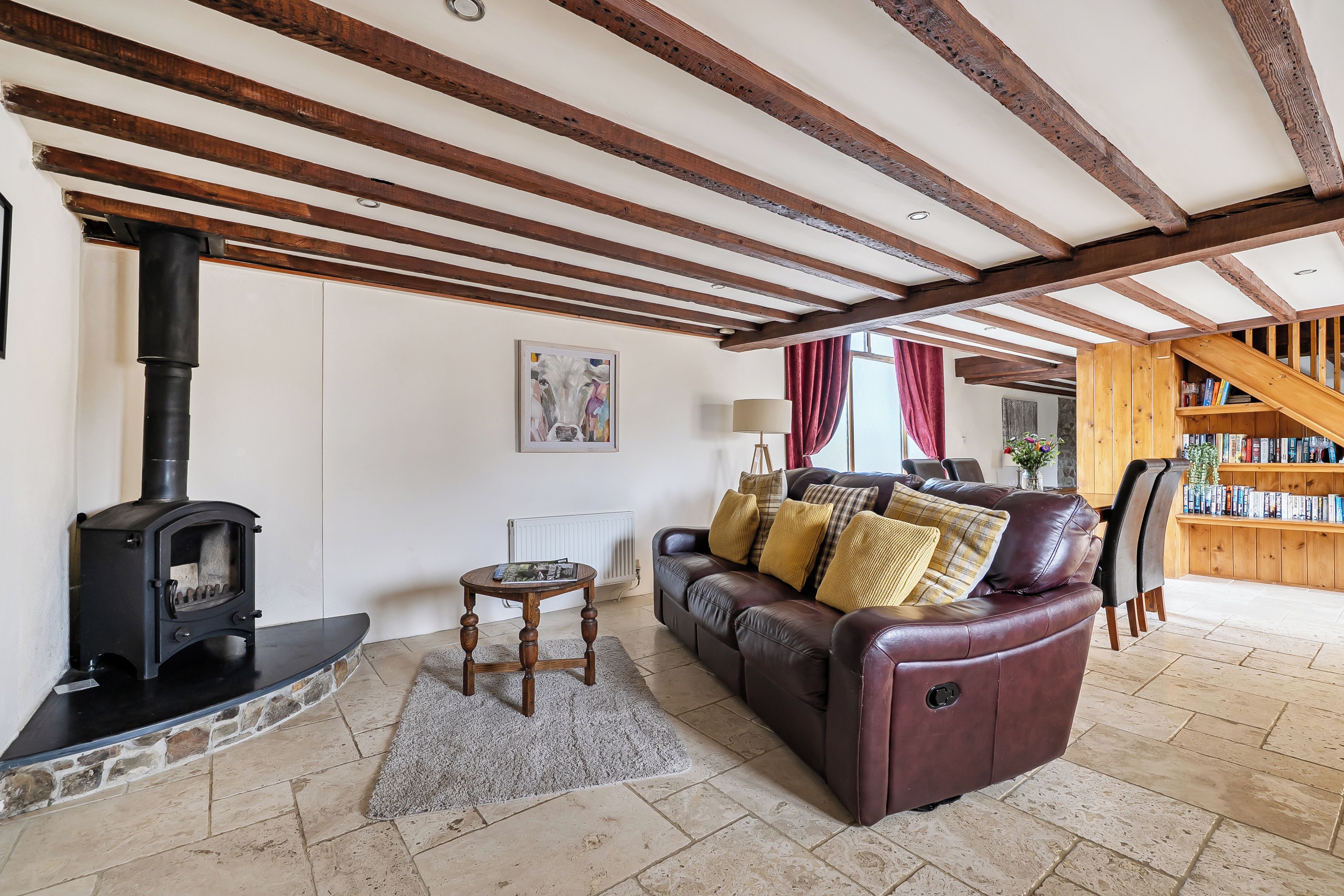 Una sala de estar acogedora con chimenea, sofá de cuero y una estantería.