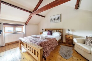 Un dormitorio con una cama de madera, una mesita de noche, una lámpara, un ventanal y un cuadro en la pared.