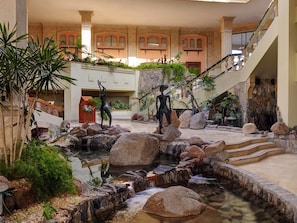 Un jardín interior con fuente de agua, escalones de piedra y esculturas.