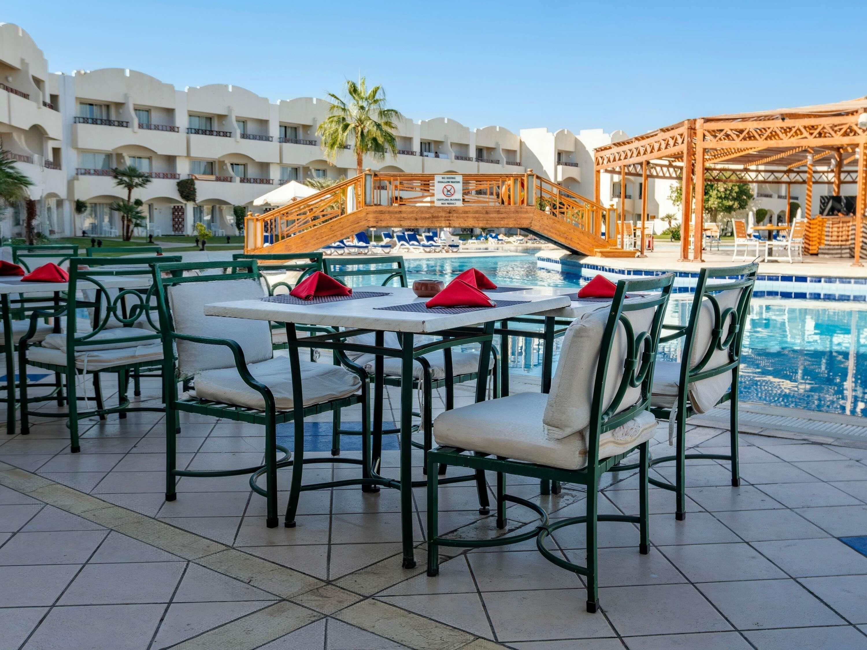 A poolside area with outdoor seating and a wooden bridge.