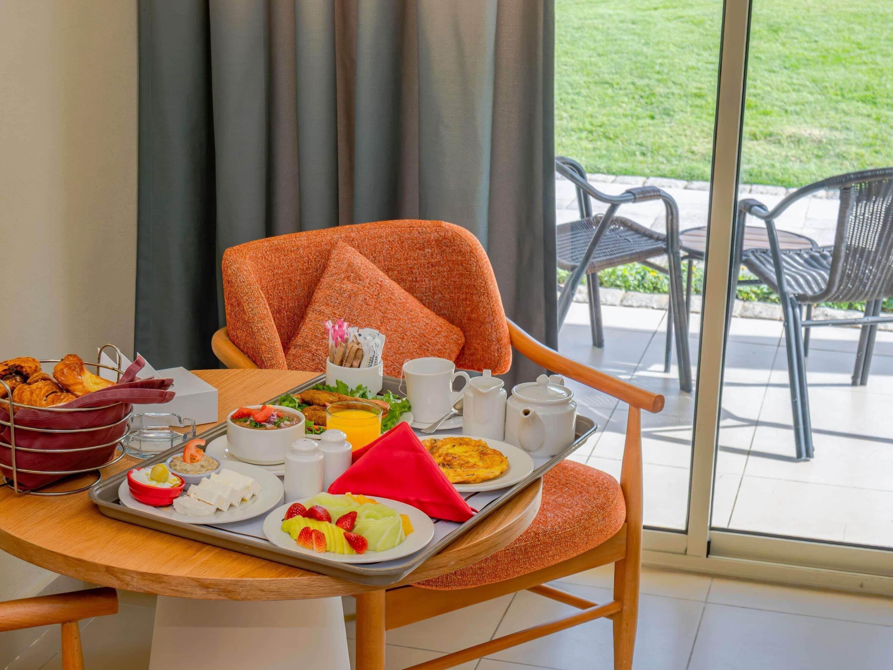 A dining table with breakfast items, a chair, and a view of the outdoors.