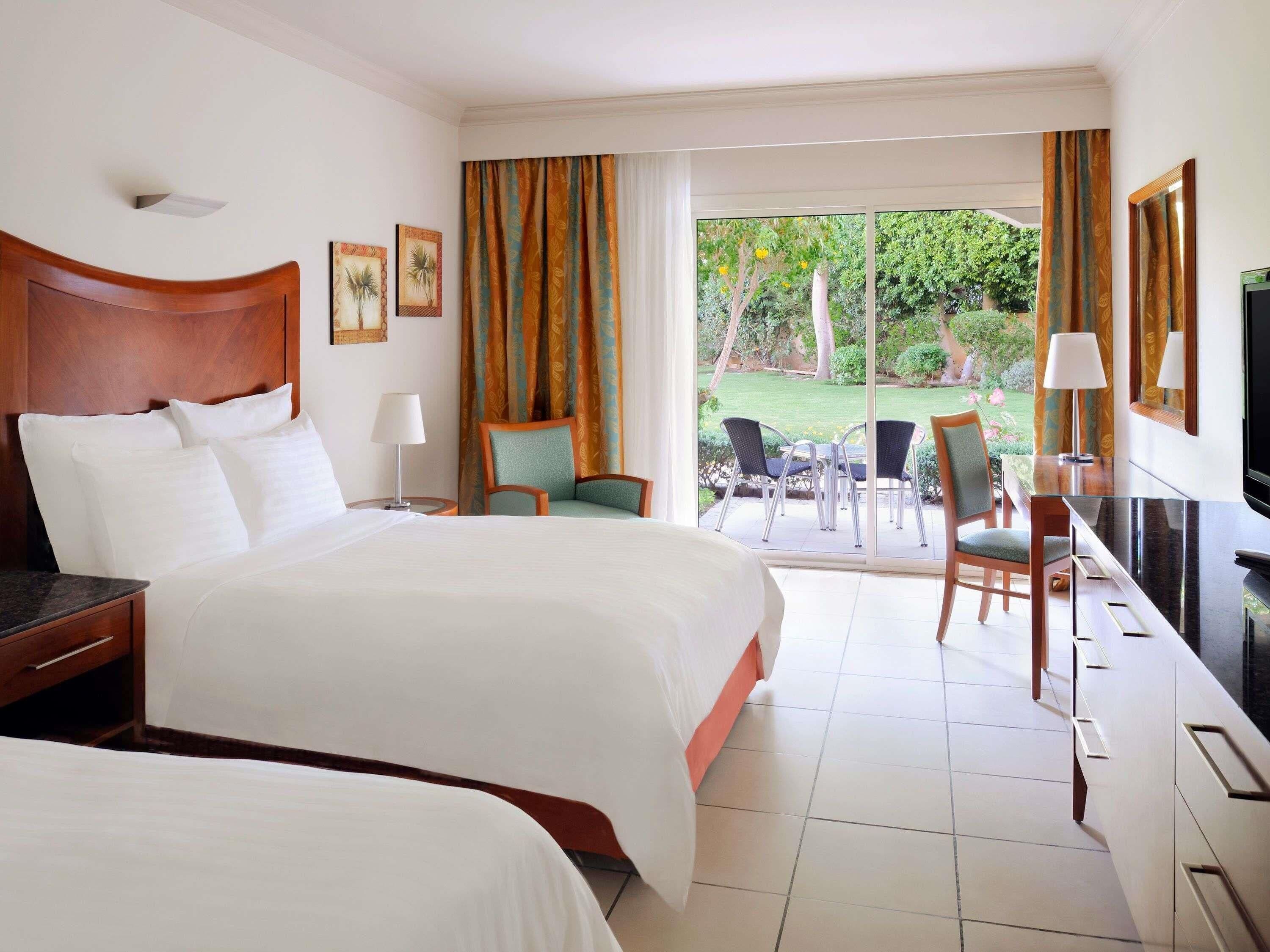 Une chambre d’hôtel équipée d’un lit, d’un bureau, d’une chaise, d’une télévision et offrant une vue sur l’extérieur.