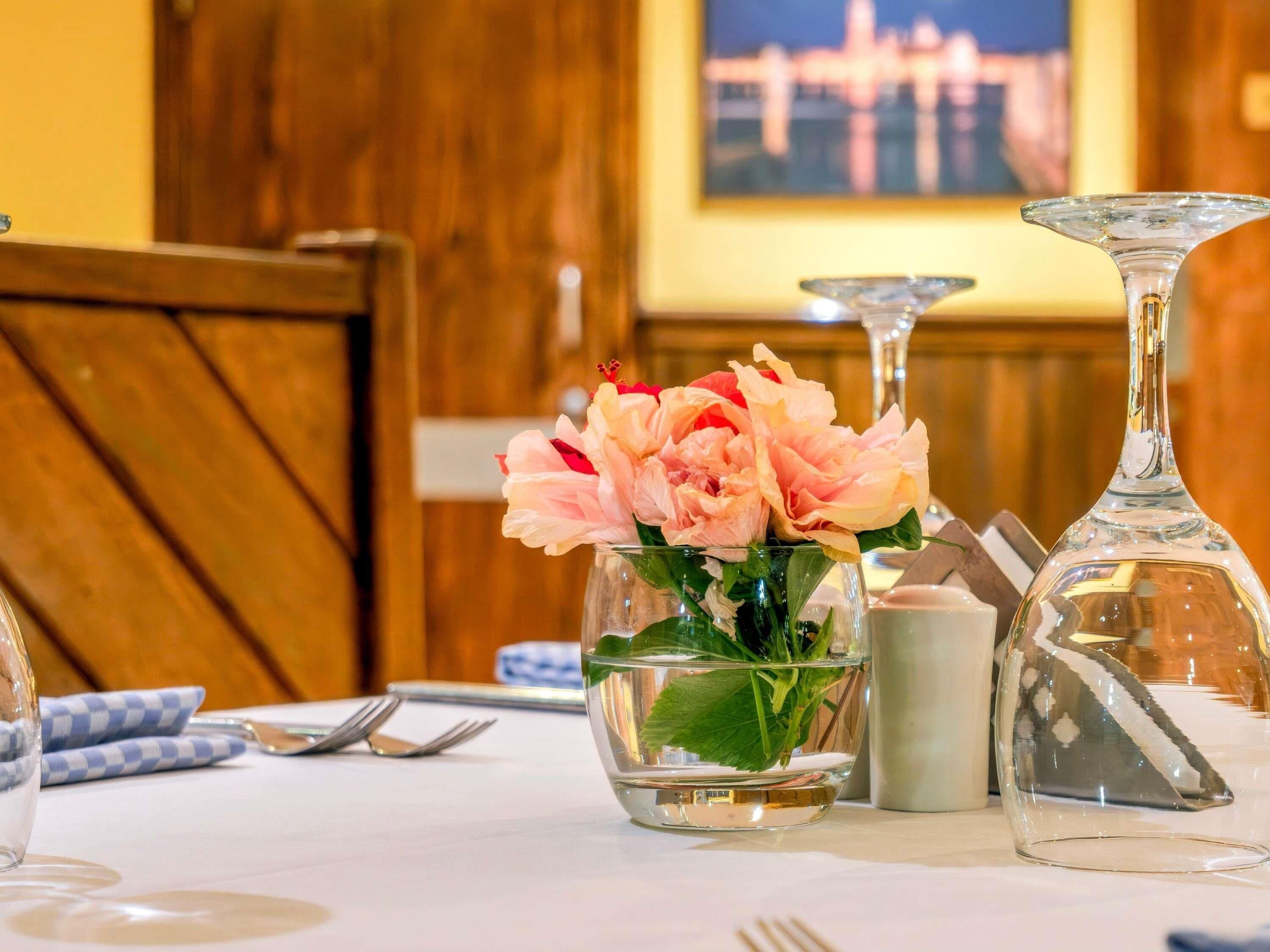 A dining table with a vase of flowers, a salt and pepper shaker, and a wine glass.