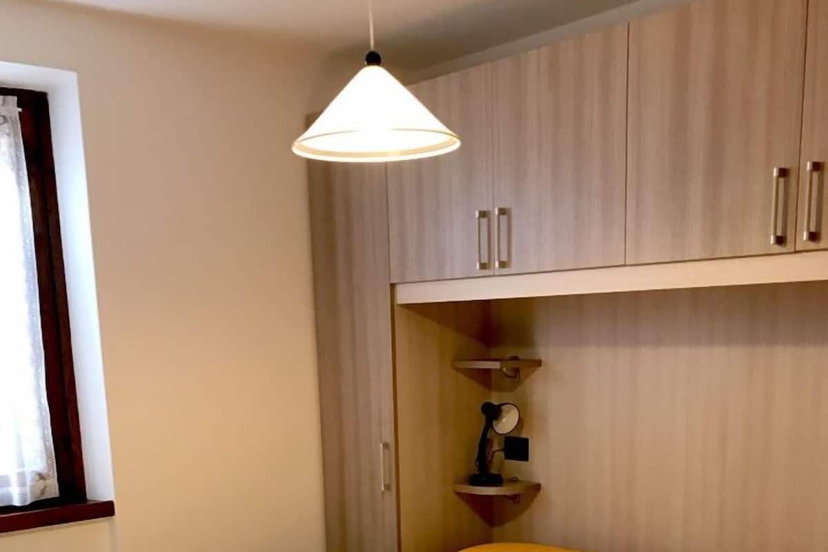 Une chambre à coucher avec un lit, un luminaire suspendu et des armoires en bois.