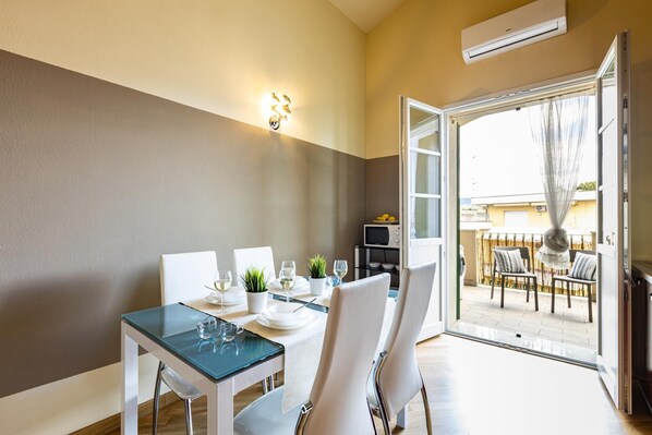 A dining area with a table set for two, a microwave, and a view of the outdoor seating area.