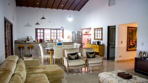 Un vaste espace de vie comprenant un canapé, une table à manger avec des chaises et un coin cuisine équipé d’un réfrigérateur et d’une fenêtre.