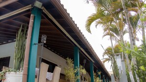 Un espace extérieur abrité, agrémenté de grands jardinières, de chaises et d’un bâtiment doté d’un toit en tuiles.
