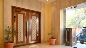 A hotel entrance with a double door, potted plants, and a parked car outside. - Hotel Regency Square (Gwalior)