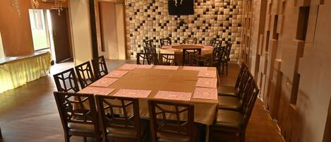 A conference room with a large table, chairs, a TV mounted on the wall, and decorative hanging plants.