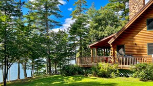 A log cabin with a deck overlooking a lake, surrounded by trees. - Waterfront log cabin nestled in the woods providing unparalleled privacy (Harpswell)