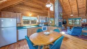 A wooden cabin interior with a kitchen, dining area, and living room. - Waterfront log cabin nestled in the woods providing unparalleled privacy (Harpswell)