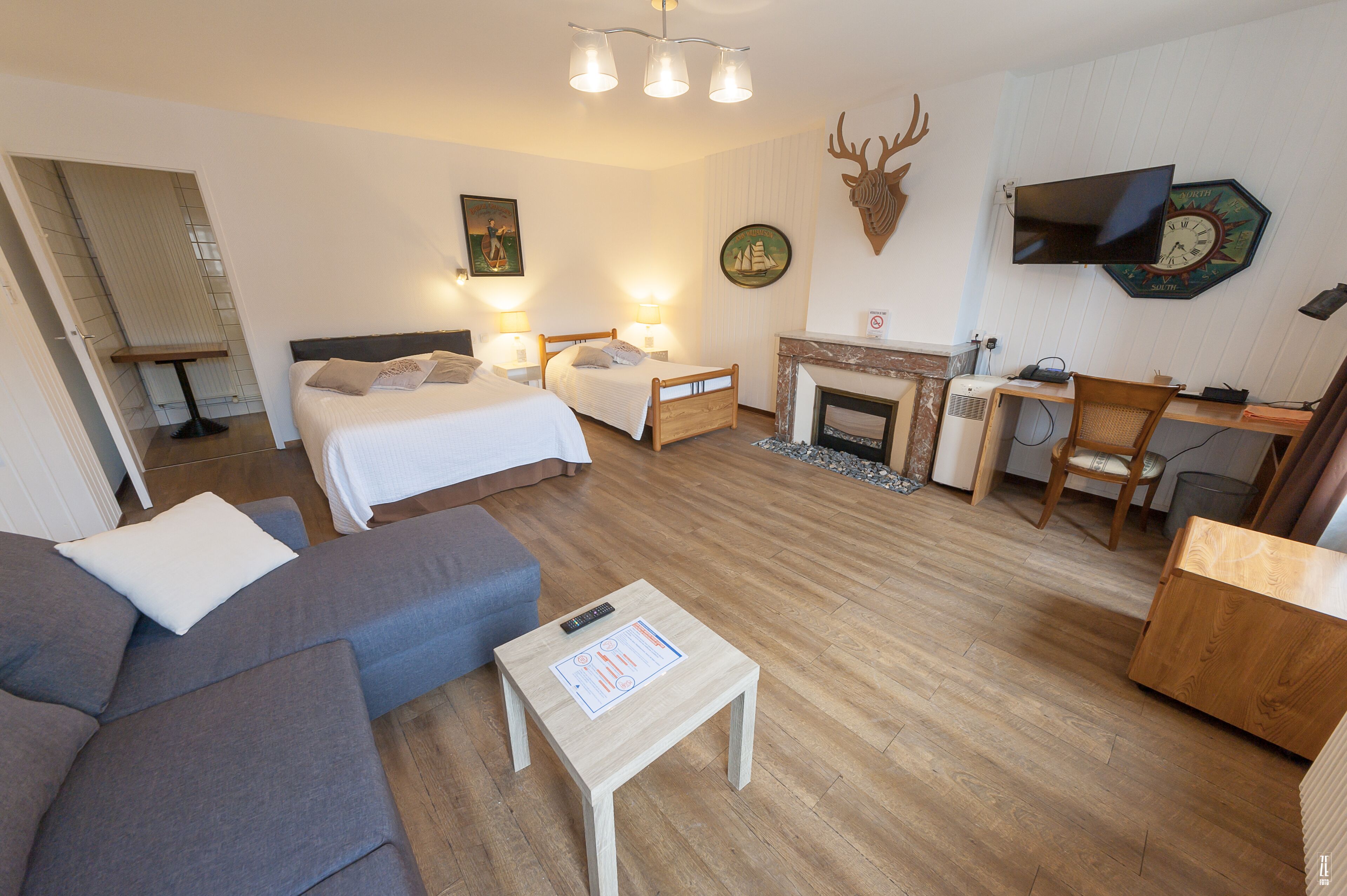 Une chambre d’hôtel avec un lit, un canapé, un bureau et une cheminée.