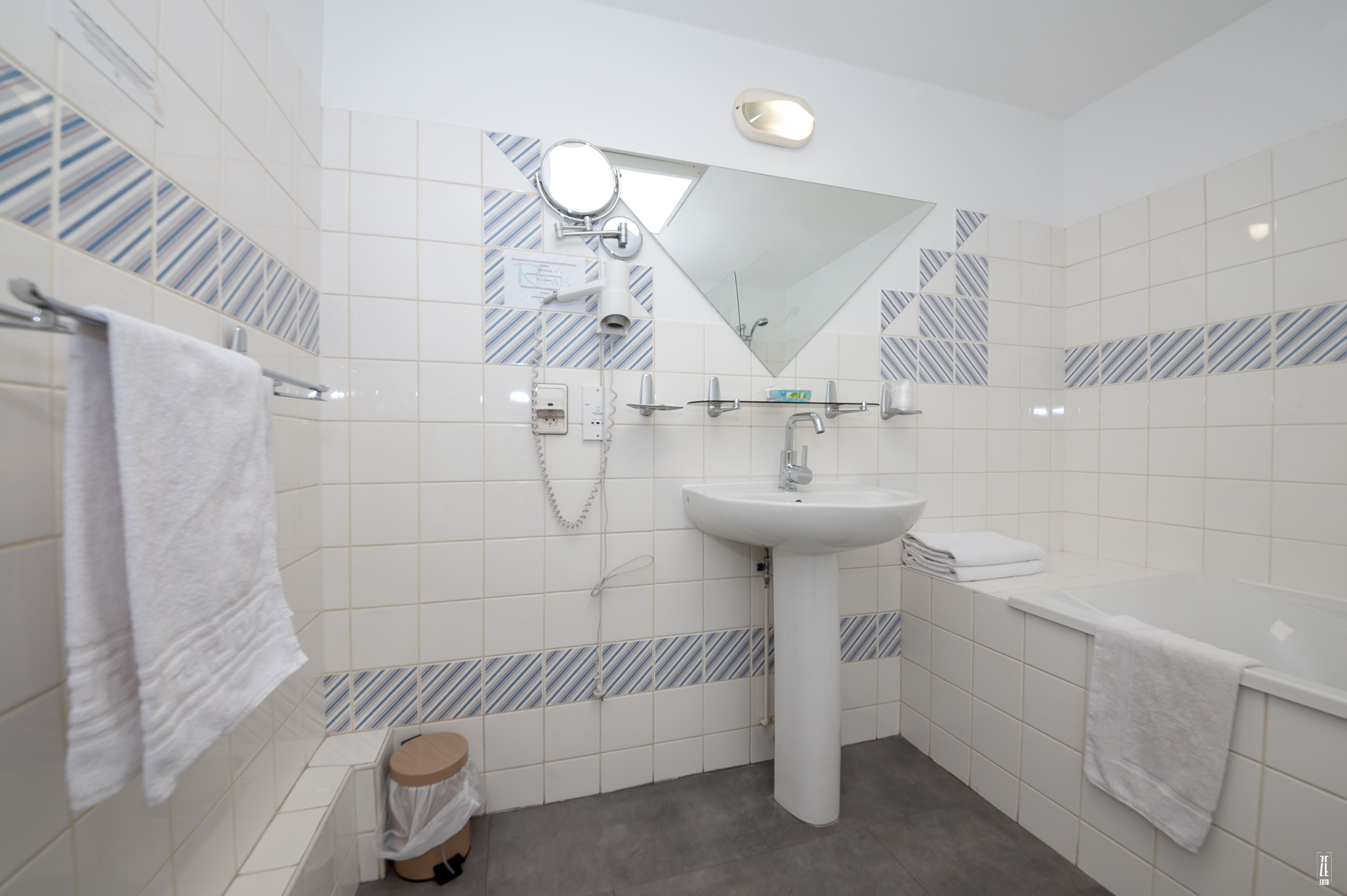 Un baño moderno con lavamanos blanco, espejo y toallero.
