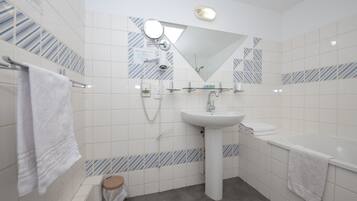 Un baño moderno con lavamanos blanco, espejo y toallero.