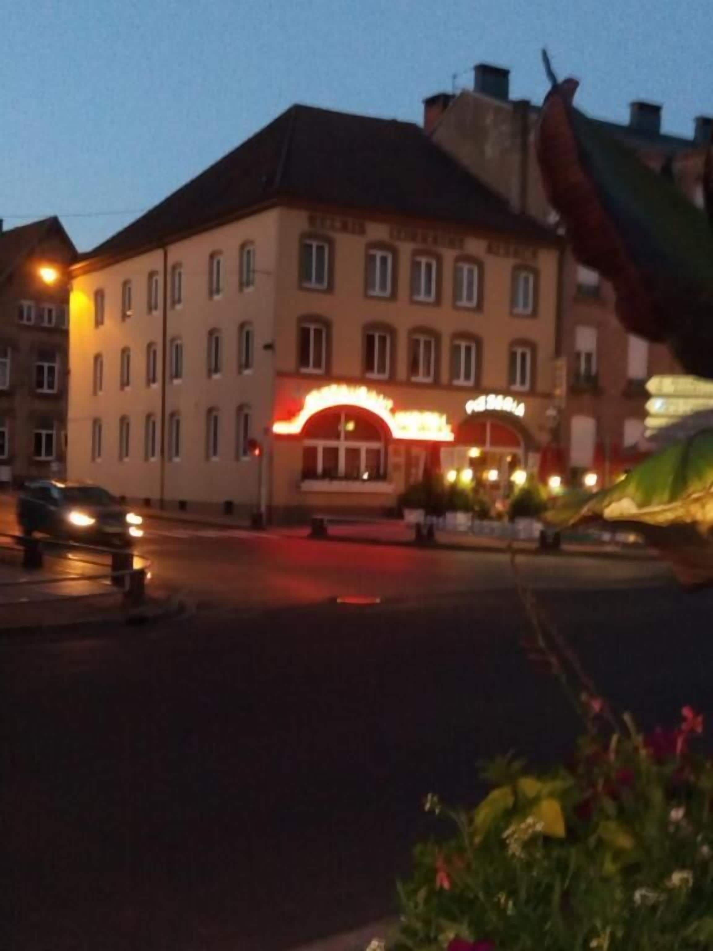 Een gebouw met een rood neonbord, meerdere ramen en een duidelijke ingang.