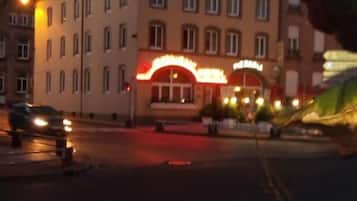 Een gebouw met een rood neonbord, meerdere ramen en een duidelijke ingang.