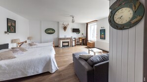 A well-lit room with a fireplace, a bed, a sofa, and a wall clock. - Relais Lorraine Alsace (Raon-l'Etape)