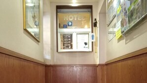 A hotel reception area with a reception desk, a glass door, and a bulletin board on the wall. - Relais Lorraine Alsace (Raon-l'Etape)