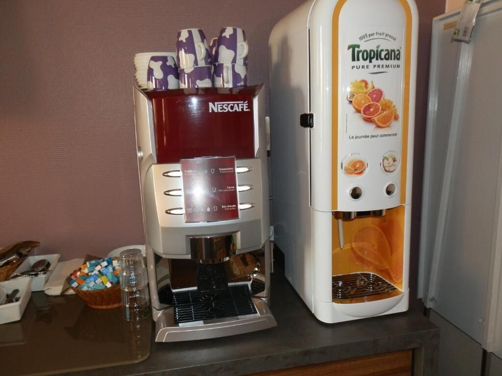 A coffee machine with a Nescafé dispenser and a Tropicana water dispenser on a kitchen counter.