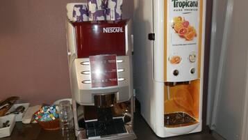 A coffee machine with a Nescafé dispenser and a Tropicana water dispenser on a kitchen counter.