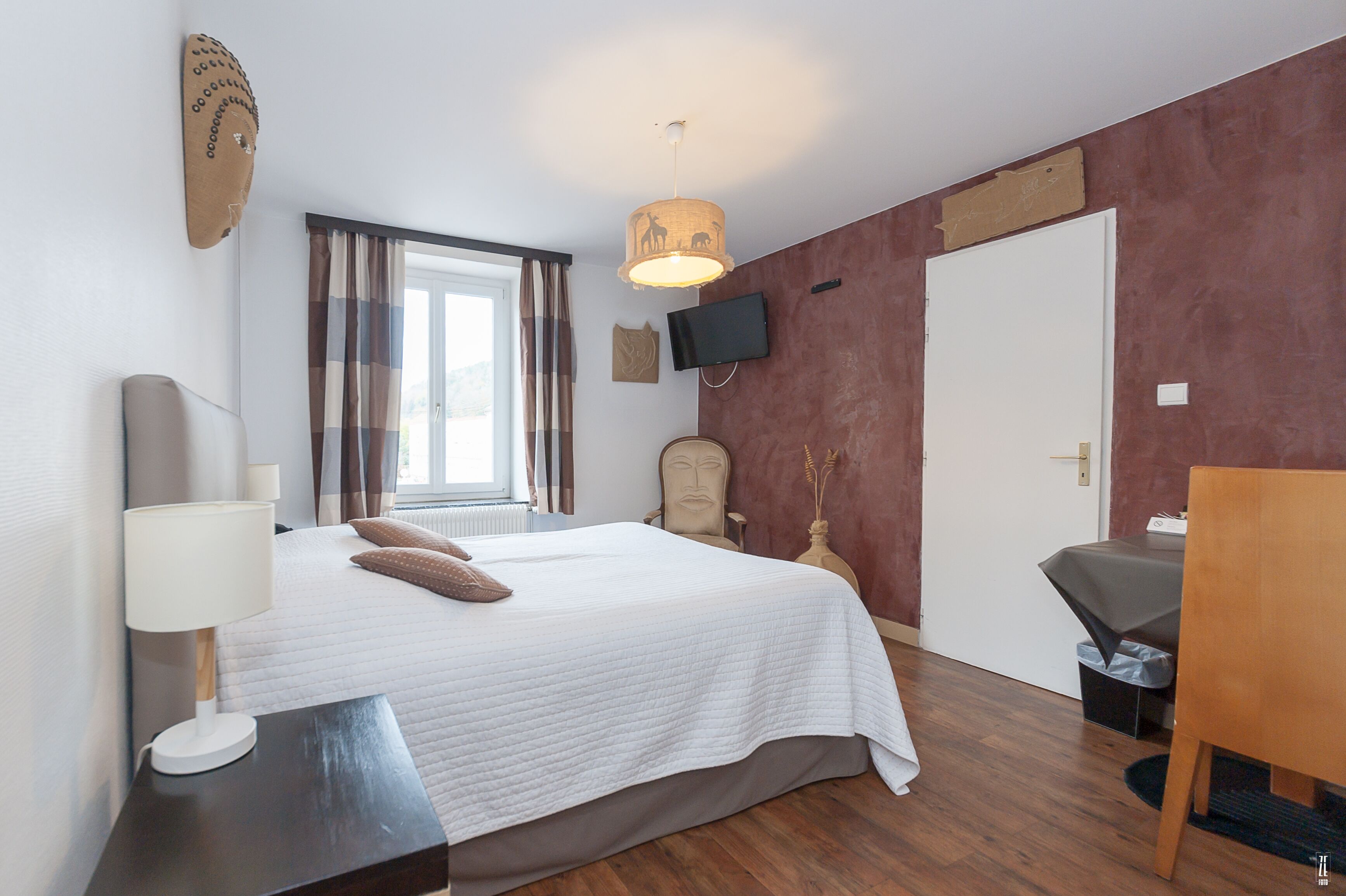 Ein Hotelzimmer mit Bett, Fernseher, Schreibtisch und Stuhl.