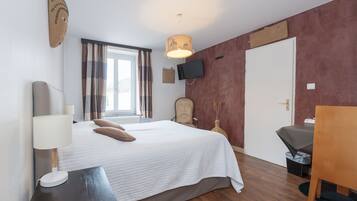Ein Hotelzimmer mit Bett, Fernseher, Schreibtisch und Stuhl.