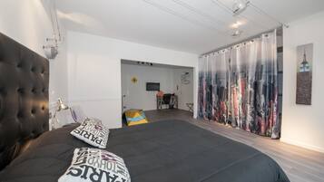 A modern bedroom with a large bed, a television, and a curtain with a cityscape design.