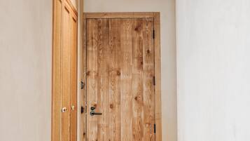 A hallway with a wooden door, a small bench, and a hanging basket.