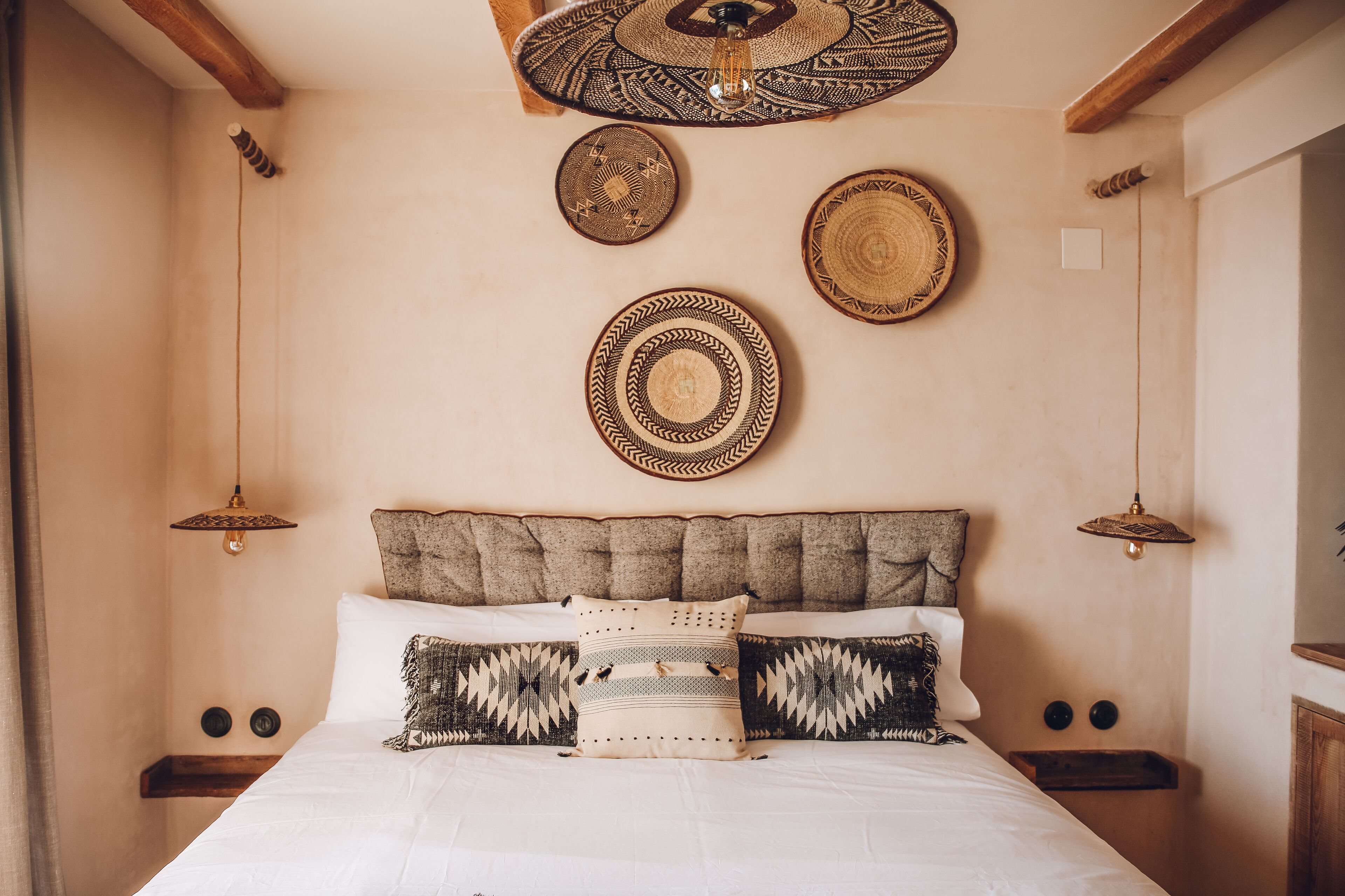 Ein Schlafzimmer mit Bett, Kissen und Kopfteil. An den Wänden sind Dekorationen und eine Deckenleuchte angebracht.