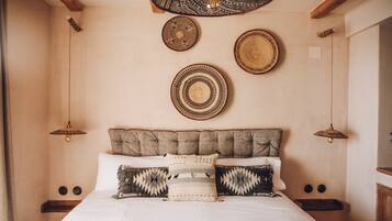 A bedroom with a bed, pillows, and a headboard. There are wall decorations and a ceiling light fixture.
