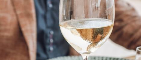 A table with a glass of white wine, a plate of food, and a napkin.