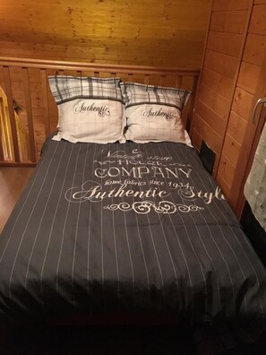 Un lit avec une couvre-lit et des oreillers à rayures noires et blanches, portant l’inscription « Authentique ».