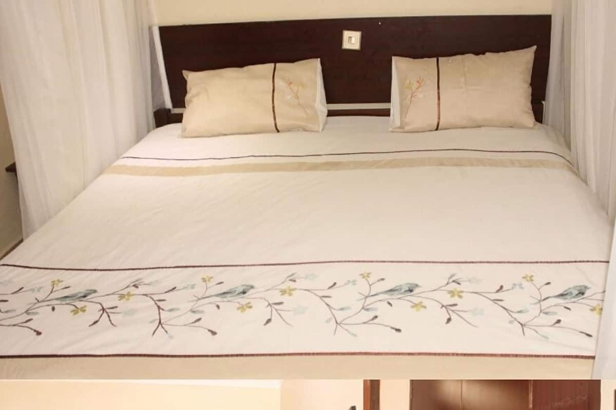 Un lit à baldaquin, deux oreillers et une couvre-lit à motifs floraux.