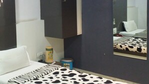 A modern hotel room with a bed, a nightstand, a mirror, and a wardrobe. - Hotel Decent (Surat)
